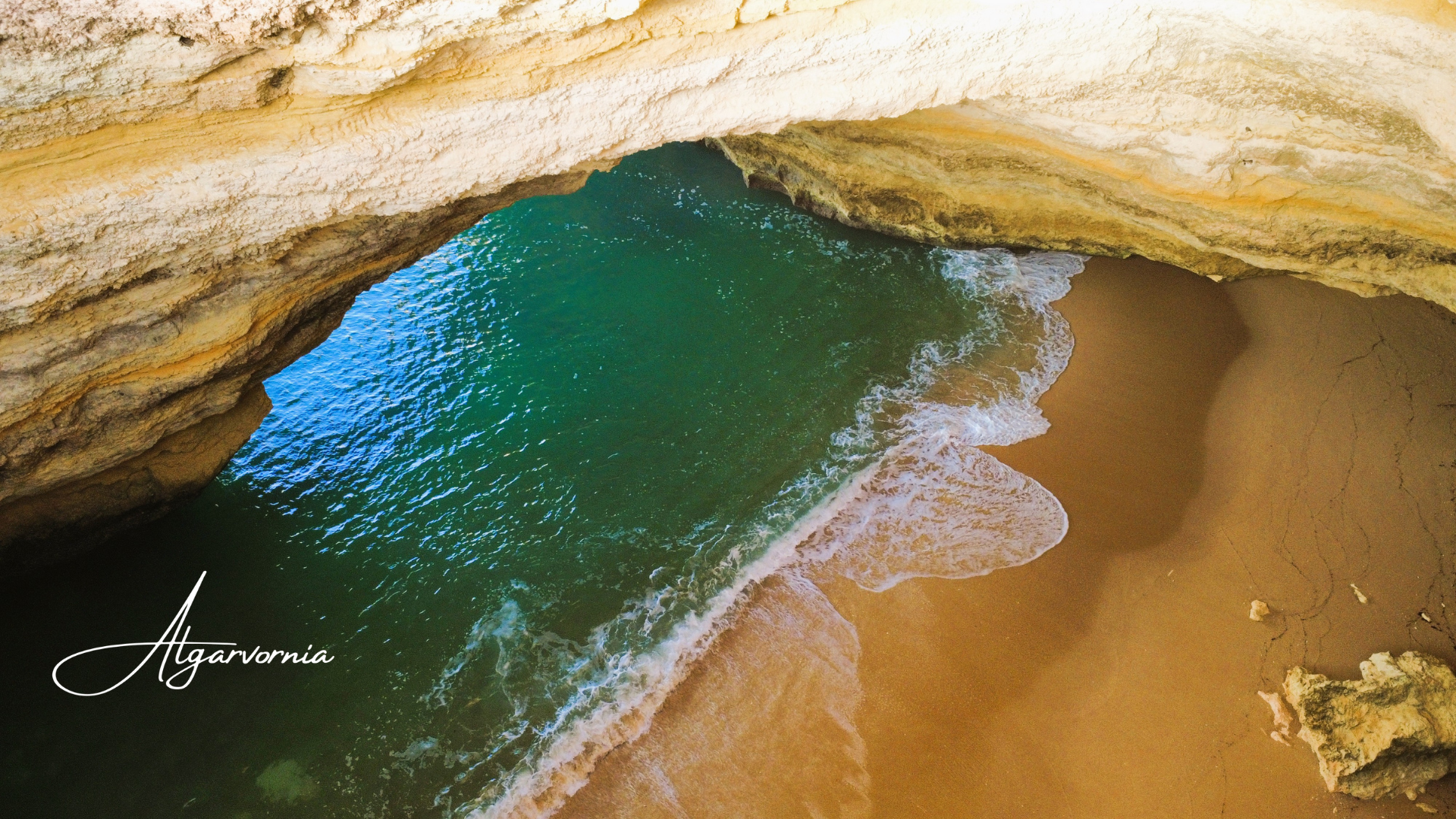 the inside of a sea cave showing the entrance, ocean water and a beach